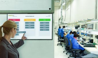 Digitales Shopfloor Board in der Fertigung zeigt Mitarbeiterin den Fortschritt der Produktion an.