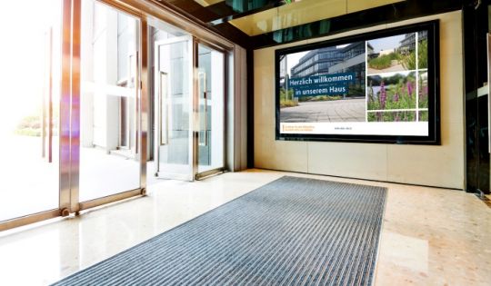 Ein Empfangsmonitor begrüßt und informiert Besucher in einer Bank