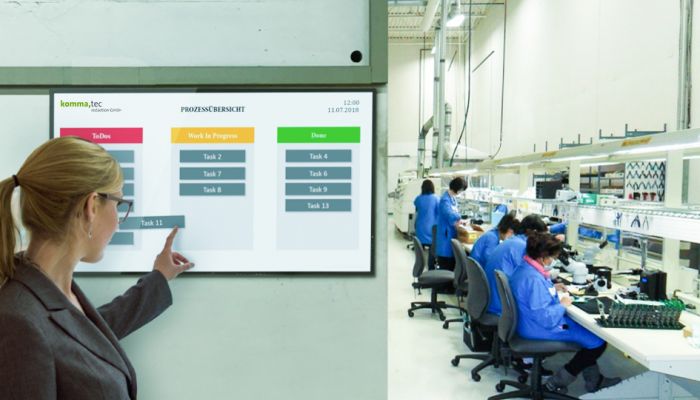 Digitales Shopfloor Board in der Fertigung zeigt Mitarbeiterin den Fortschritt der Produktion an.
