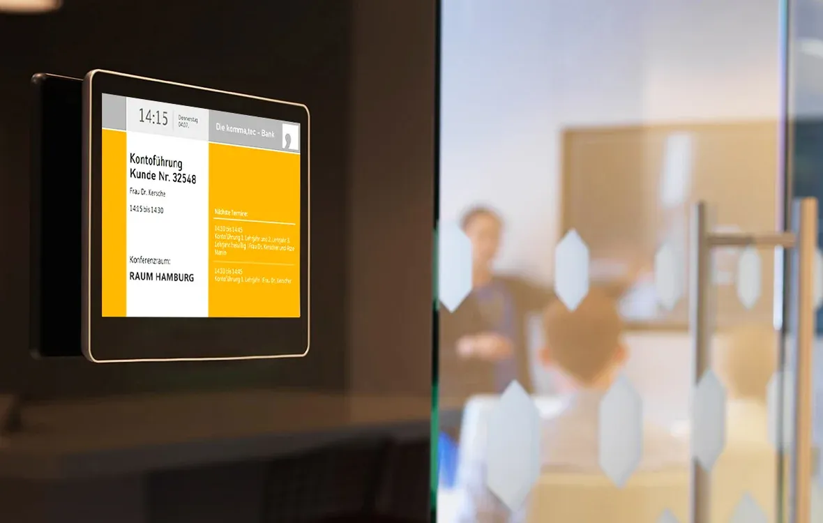Digitales Türschild zeigt aktuelle Konferenzraumbelegung und Kundentermine in einer modernen Büroumgebung.