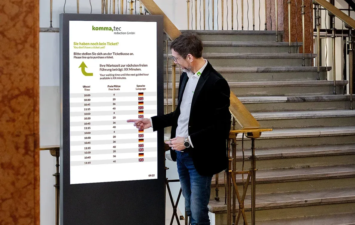 Der Geschäftsführer der komma,tec redaction berührt eine digitale Stele im Rathaus.