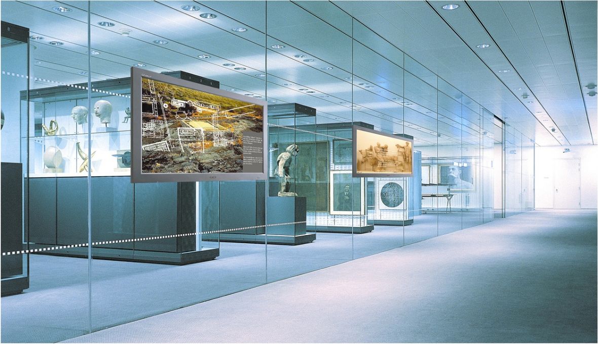 Digital Signage Infoboards in einem modernen Museum präsentieren historische Inhalte und interaktive Informationen in einer hochwertigen, gläsernen Ausstellungsumgebung.