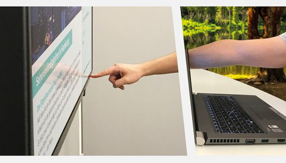 Interaktive Digital Signage Anwendung Person interagiert mit einem interaktiven Digital Signage Bildschirm, während sie einen Laptop benutzt.