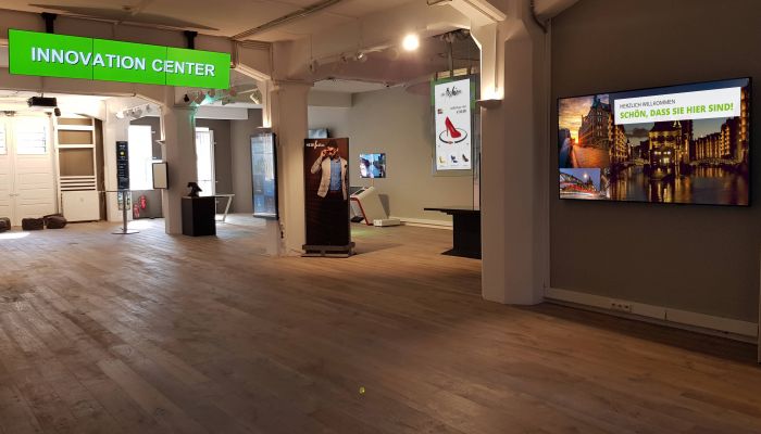 Innenansicht des Innovation Centers der komma,tec redaction, das moderne Digital Signage Displays und innovative Technologie-Lösungen in einer großzügigen Ausstellungsfläche präsentiert.