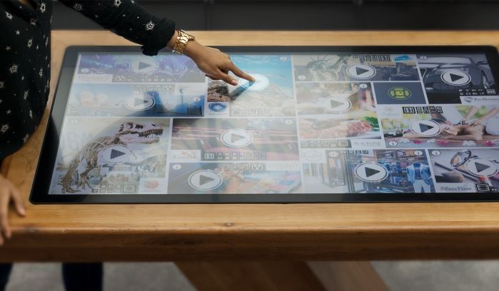 Ein interaktiver Touchscreen-Tisch zeigt multimediale Inhalte wie Videos und Bilder.