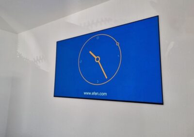 Großer Präsentationsbildschirm mit einer analogen Uhranzeige, der mit dem Präsentationsmodul verbunden ist.