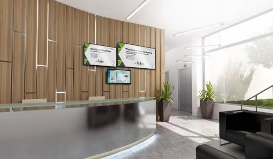 Ein heller, moderner Empfangsbereich mit zwei digitalen Displays, die Begrüßungsnachrichten auf Deutsch und Englisch anzeigen.